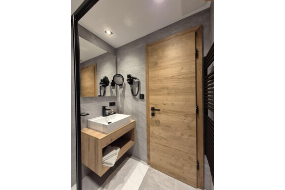 A modern bathroom with a shower. The room has bright tiles and a large mirror. - Gästehaus Maier - Sölden