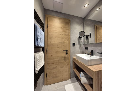 A modern bathroom with a shower. The room has bright tiles and a large mirror. - Gästehaus Maier - Sölden