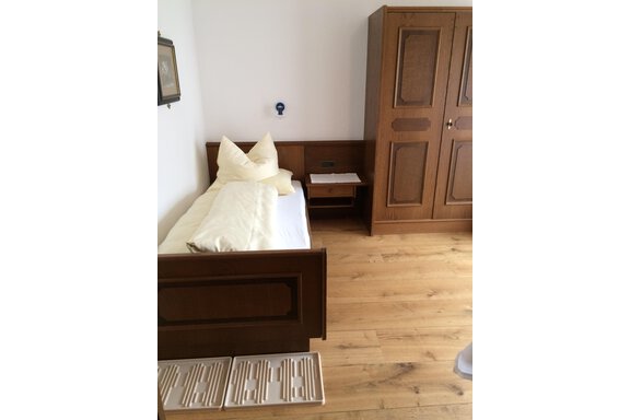 A simple room with a wooden bed and a wardrobe. The floors are made of light wood and there is a bright, inviting atmosphere. - Gästehaus Martin - Sölden