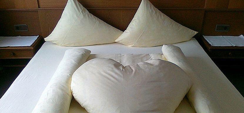 Doppelzimmer A cozy bed with two pillows and a heart-shaped comforter. The atmosphere feels romantic and inviting. - Gästehaus Martin - Sölden