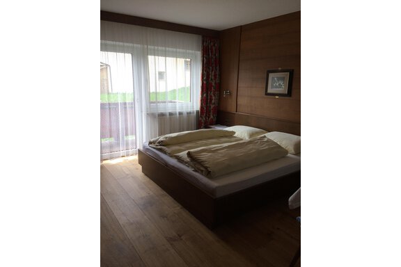 A cozy bedroom with a large bed and soft colors. Large windows let in plenty of light and offer a view outside. - Gästehaus Martin - Sölden