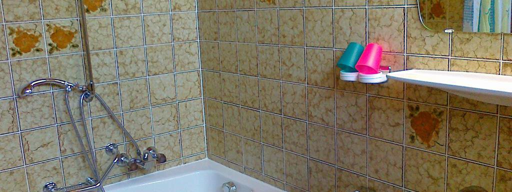 A simple bathroom with a bathtub and a sink. The walls are decorated with tiled, patterned tiles. - Gästehaus Martin - Sölden