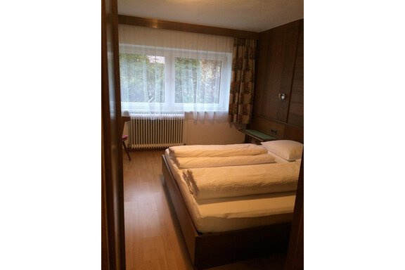 A simple bedroom with two beds and fresh linens. Large windows let in plenty of light and create a pleasant atmosphere. - Gästehaus Martin - Sölden