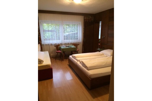 A simple room with two beds and a table. Large windows bring a lot of light into the room. - Gästehaus Martin - Sölden
