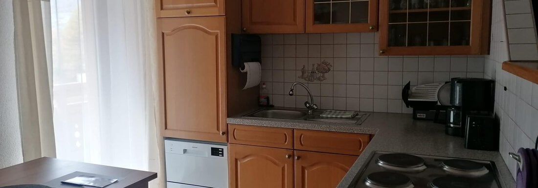 A modern kitchen with wooden cabinets and a bright atmosphere. The dining area is simply and invitingly designed. - Gästehaus Sternberger - Sölden