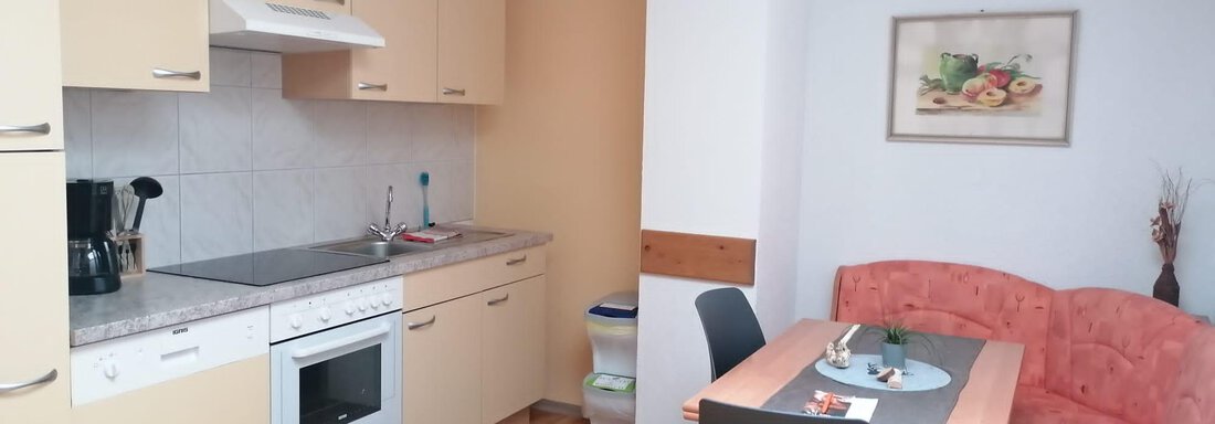 A modern kitchen with bright cabinets and a dining table. The decor is simple and inviting. - Gästehaus Sternberger - Sölden