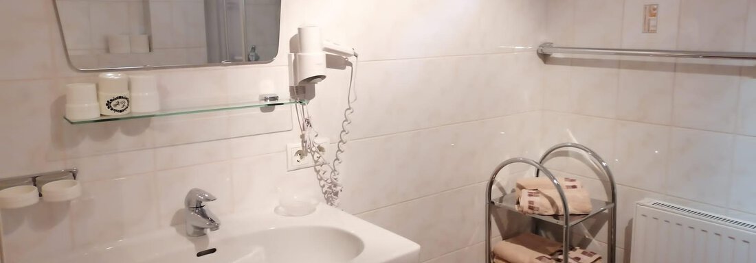 A modern bathroom with a sink and a large mirror. Towels are neatly arranged in a roll cart next to the sink. - Gästehaus Sternberger - Sölden