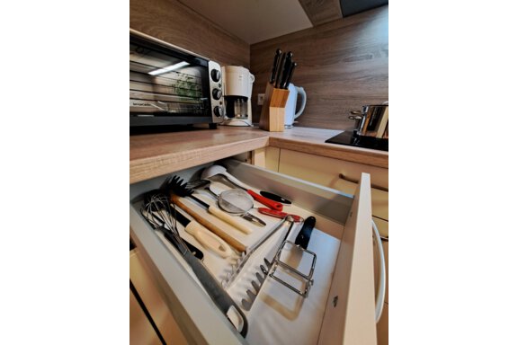 A modern kitchen with an open drawer full of cooking utensils. Next to the drawer, a toaster and a kettle are placed on the countertop. - Gästeheim Schmiedhof - Sölden