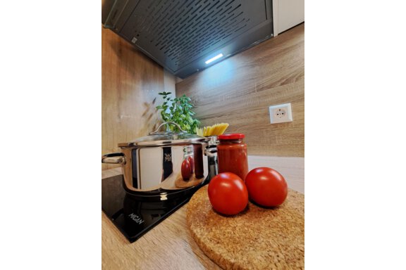 A modern kitchen with a pot, fresh tomatoes, and a glass of tomato sauce. In the background, fresh herbs and a wooden surface can be seen. - Gästeheim Schmiedhof - Sölden
