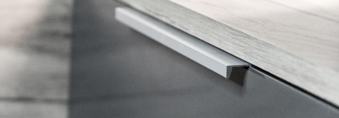 A close-up of a modern metal furniture handle. The handle is set against a simple, light surface. - Gästeheim Schmiedhof - Sölden