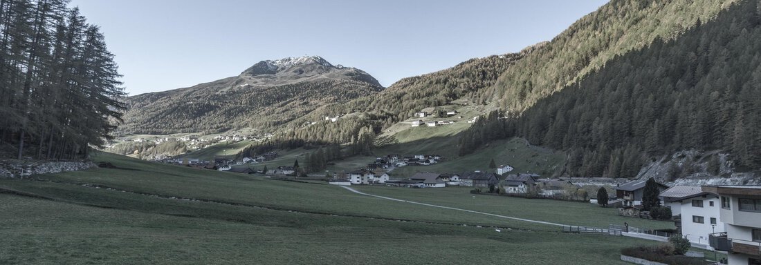 A tranquil landscape with green meadows and high mountains in the background. The image depicts a peaceful alpine setting. - Gästeheim Schmiedhof - Sölden