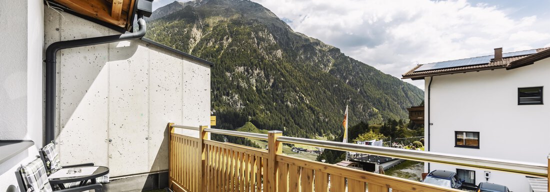 A balcony with a wooden railing and a view of the mountains. The clouds are partially visible and the atmosphere is calm. - Gasthof Granstein - Sölden