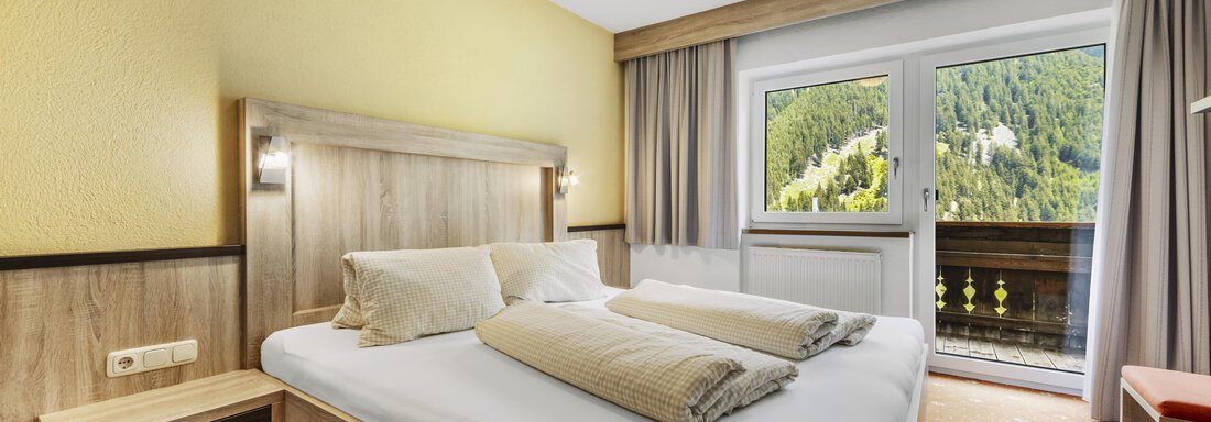 _F0A8113 A cozy bedroom with a double bed and two pillows. Through the windows, there is a beautiful view of the surrounding mountains. - Gasthof Granstein - Sölden