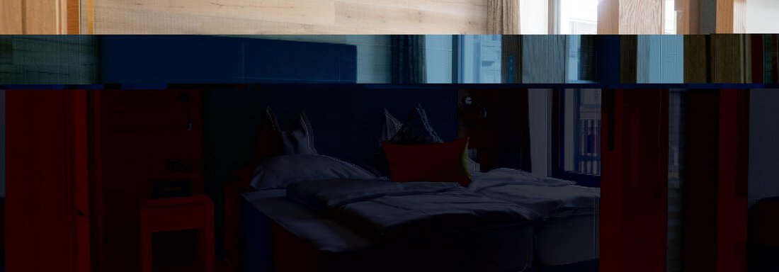 Ein modernes Schlafzimmer mit einem großen Bett und Holzverkleidung. Weiches Licht strömt durch das Fenster und schafft eine gemütliche Atmosphäre. - Glanz & Glory Hotel - Sölden