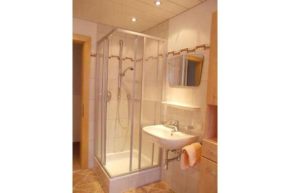 A modern bathroom with a shower cabin and a wash basin. The walls are tiled and the lighting is bright. - Gstrein Andreas - Sölden