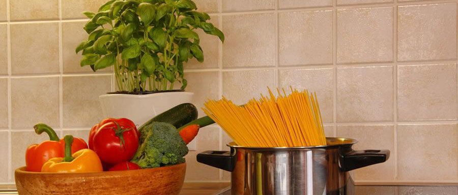 A cooking pot with spaghetti is on the stove. In a bowl beside it, fresh vegetables and herbs are lying. - Haus Alpenstern - Sölden