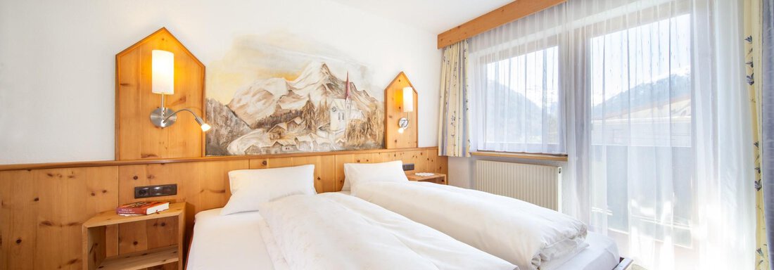 A bright room with two single beds and wooden decor. Large windows offer a beautiful view of the mountains. - Haus Alpenstern - Sölden