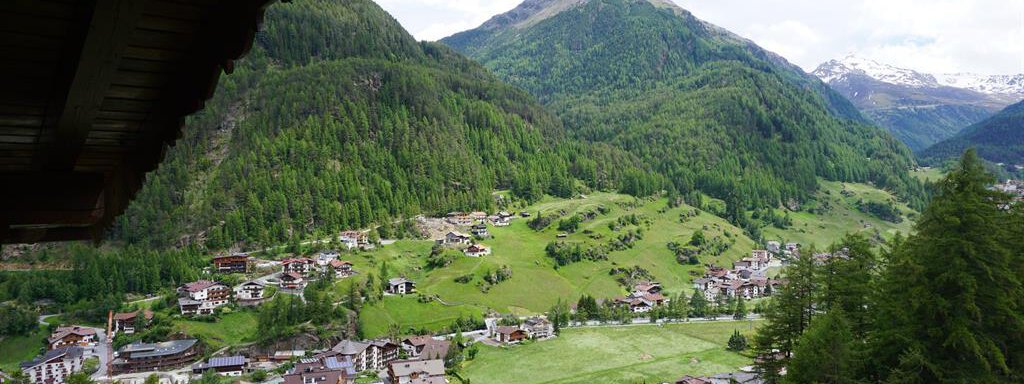 A beautiful view of a picturesque village in the mountains. The lush green hills and the clear sky complete the serene landscape. - Haus Alpenstern - Sölden