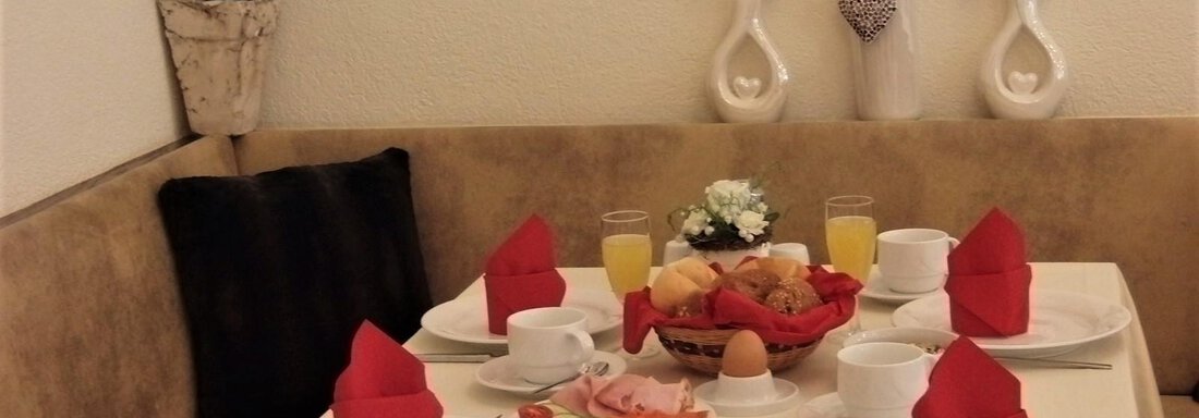 A laid table with a lavish breakfast. There are fresh rolls, cold cuts, boiled eggs, and drinks arranged. - Haus Amaris - Sölden