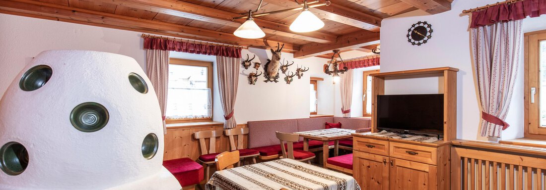 Stube A cozy room with wood paneling, a large table, and a traditional oven. The decor is rustic and warm, perfect for sociable evenings. - Haus Bergblick - Sölden