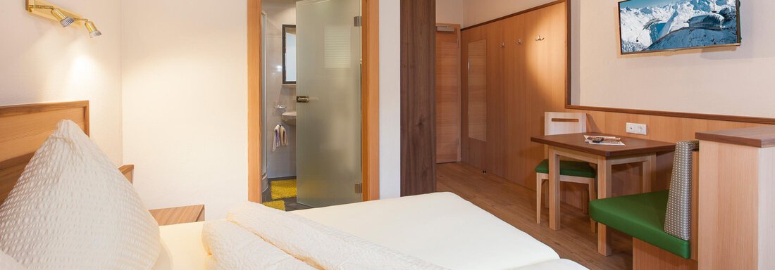A modern hotel room with two beds and a small table. The walls are bright and the decor is cozy. - Haus Bergblick - Sölden