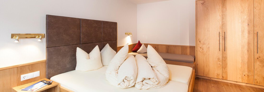 A cozy bedroom with a double bed and wooden furniture. The walls are light, and the room is well lit. - Haus Bergblick - Sölden
