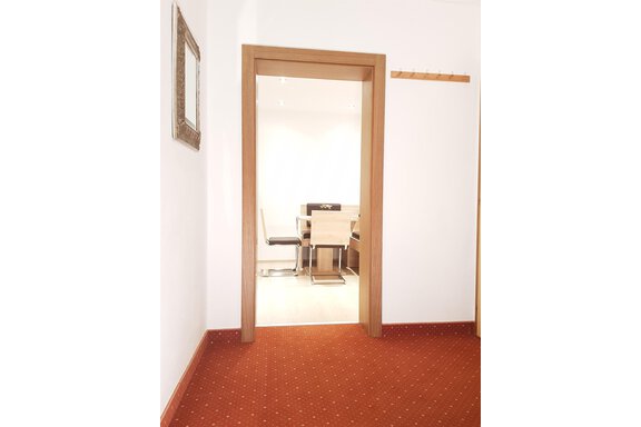 A bright hallway with a wooden frame and access to a dining area. The floor is covered with red carpet. - Haus Christian - Sölden