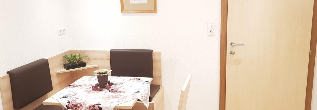 A cozy dining area with a table and chairs in a bright environment. A blooming picture hangs on the wall, and the door is made of wood. - Haus Christian - Sölden