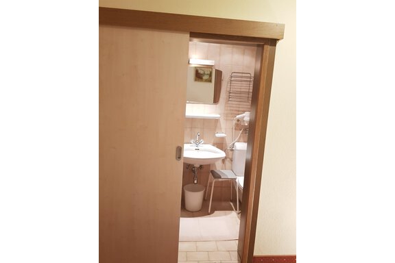 A small bathroom with a sink, a toilet, and a towel holder. The walls are painted in neutral tones. - Haus Christian - Sölden