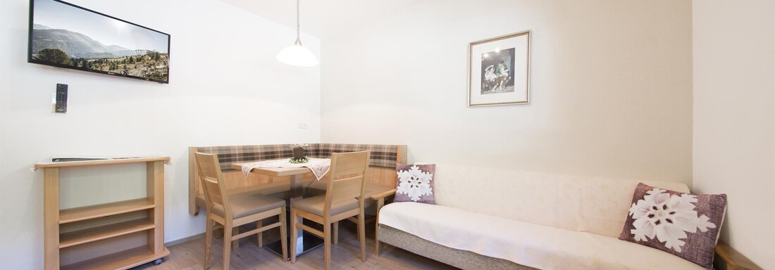 1 A modern living room with a dining area and a cozy seating corner. Pictures hang on the wall, and there is a television. - Haus Christian - Sölden