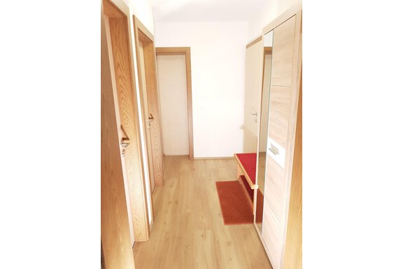 A bright hallway with wooden doors and a mirror. A red runner lies on the floor. - Haus Christian - Sölden