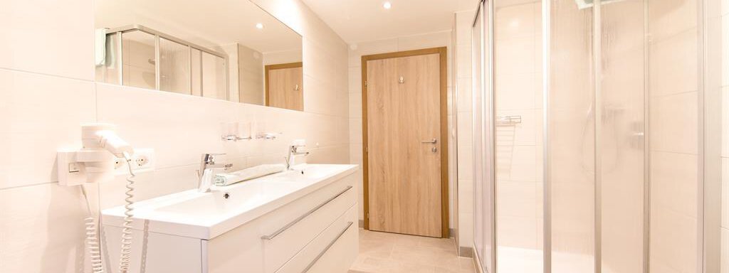 A modern bathroom with bright walls and an elegant sink. The shower cabin is transparent and the decor looks fresh and inviting. - Haus Christian - Sölden
