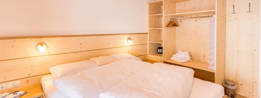 A cozy bedroom with wooden decor and a large double bed. The warm light sources create an inviting atmosphere. - Haus Edmund - Sölden