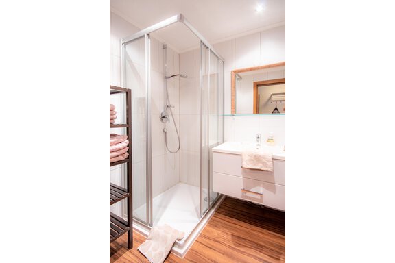 A modern bathroom with a shower and a sink. Wooden floor and clean towels create an inviting atmosphere. - Haus Edmund - Sölden