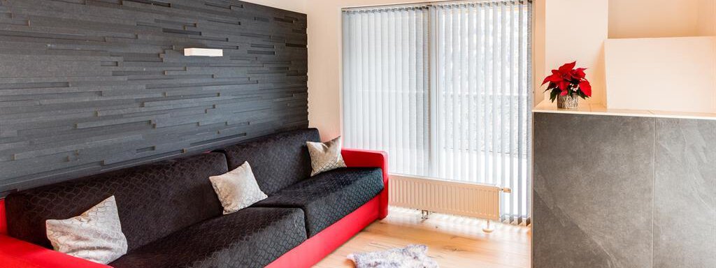 Schneerose living-kitchen 2 pers. A modern living room with a red sofa and decorative pillows. Large windows provide plenty of daylight and a bright atmosphere. - Haus Edmund - Sölden