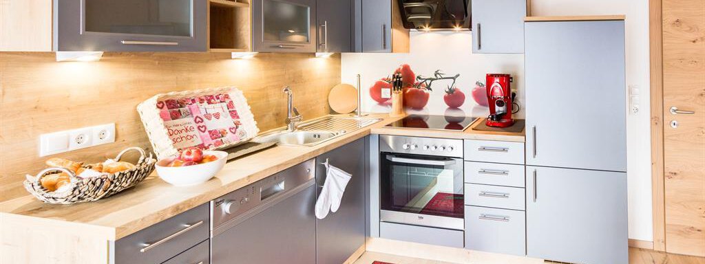 A modern kitchen with gray cabinets and light wood. It is well equipped with cooking appliances and has an inviting carpet. - Haus Edmund - Sölden