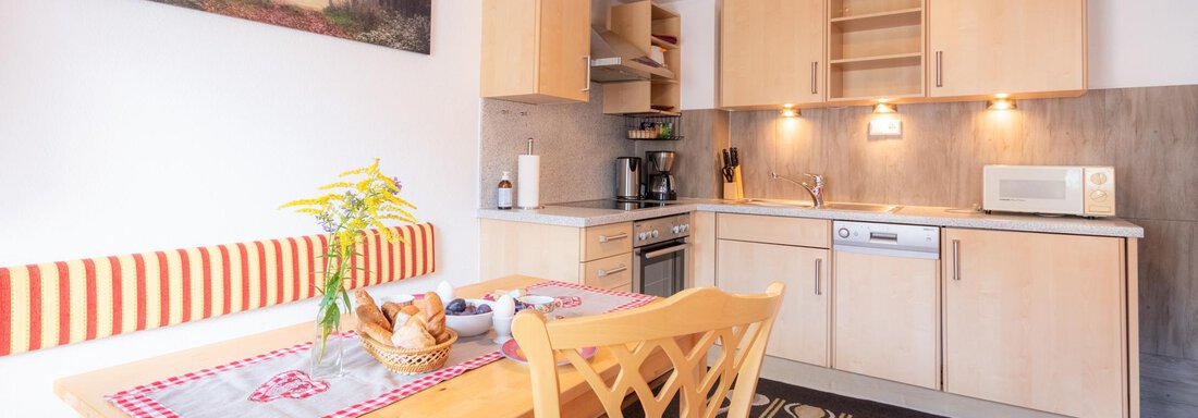 A bright kitchen with modern appliances and a cozy dining area. The walls are painted in soft colors, and a picture of a deer adorns the wall. - Haus Edmund - Sölden
