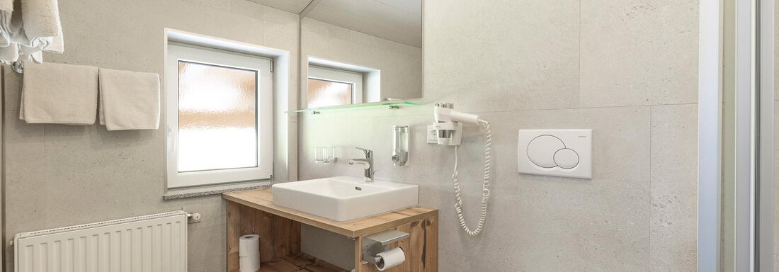 A modern bathroom with bright and functional furnishings. There is a sink, a shower, and a toilet area. - Haus Falkner Ignaz - Sölden