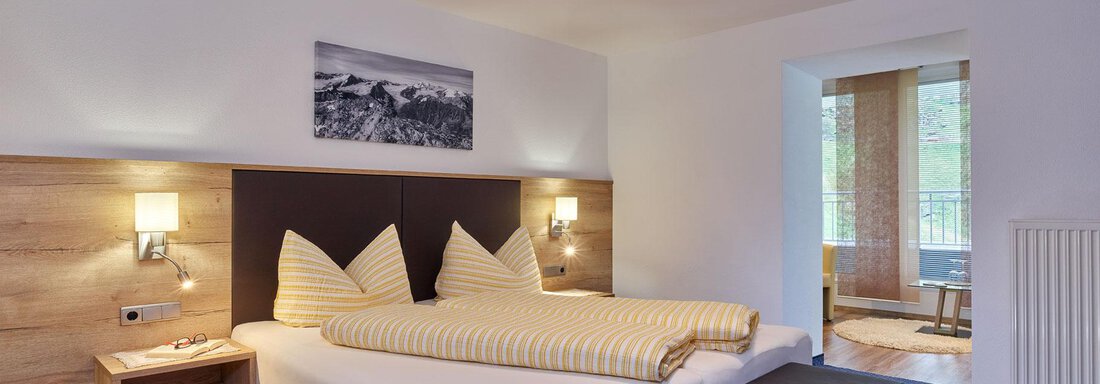 A modern bedroom with a large bed and cozy furnishings.  
Large windows provide plenty of daylight and an inviting atmosphere. - Haus Fontana - Sölden