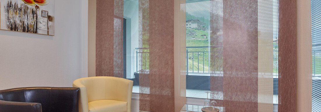 A cozy living space with a black and a yellow armchair. Large windows with semi-transparent curtains let in plenty of light. - Haus Fontana - Sölden