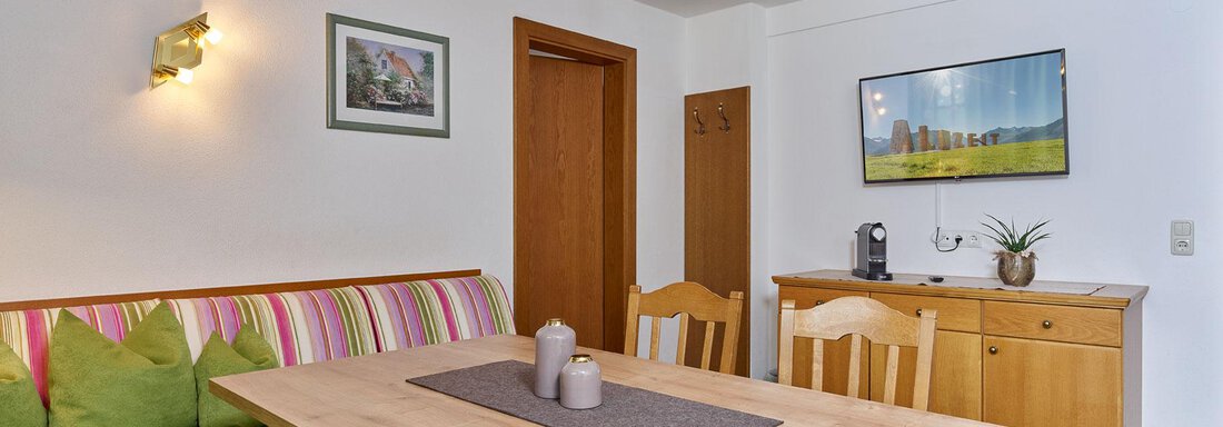 An inviting dining room with a large wooden table and comfortable seating. The walls are painted light and decorated with pictures and a modern view. - Haus Fontana - Sölden