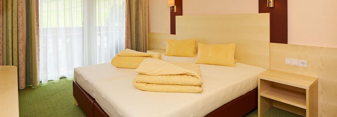 A modern bedroom with a large double bed and bright, friendly interior. Large windows allow plenty of daylight to enter and offer a view of the outdoors. - Haus Fridolin - Sölden