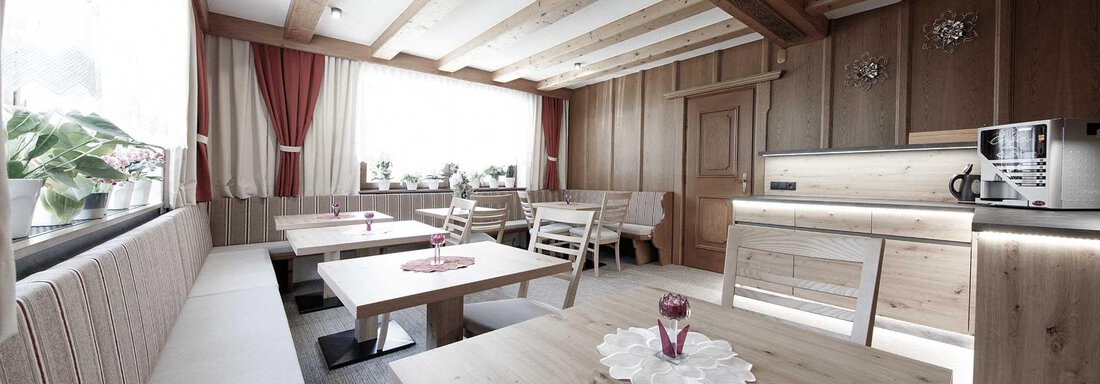 A cozy room with wooden beams and a bright, inviting atmosphere. There is a seating area and a small kitchen. - Haus Gabriela - Sölden