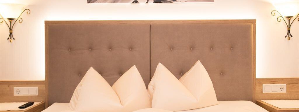 A cozy bedroom with a large double bed and modern nightstands. A picture of a climber in a winter landscape hangs on the wall. - Haus Gondelblick - Sölden