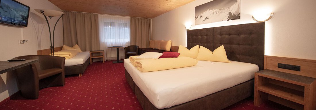 A cozy hotel room with two beds and a large window. The decor is modern and inviting, featuring a television and a seating area. - Haus Gondelblick - Sölden