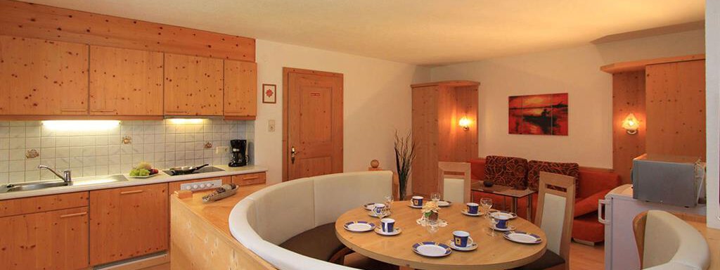 kueche_ingrid A cozy kitchen with wooden cabinets and a round dining area. The room is bright and invitingly designed. - Haus Ingrid - Sölden