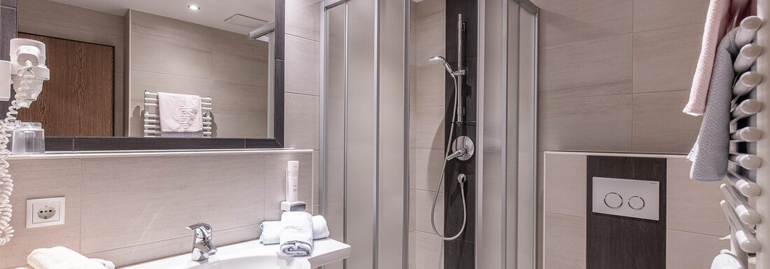 A modern bathroom with a shower and a sink. The walls are in neutral colors and the space feels bright and inviting. - Haus Manfred - Sölden