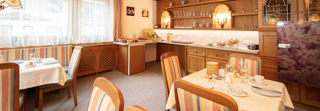 A cozy dining room with wooden furniture and striped chairs. The space is bright and inviting, with a table set for breakfast. - Haus Montjola - Sölden