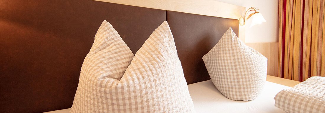 An inviting bed with two large pillows and soft bedding. Soft light creates a cozy atmosphere. - Haus Montjola - Sölden