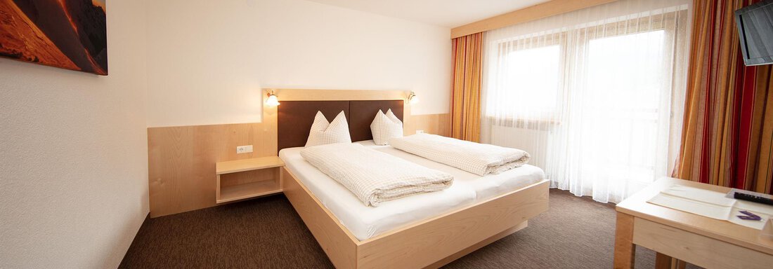 A modern hotel room with two single beds and a large window. The decor is simple and inviting, ideal for a pleasant stay. - Haus Montjola - Sölden